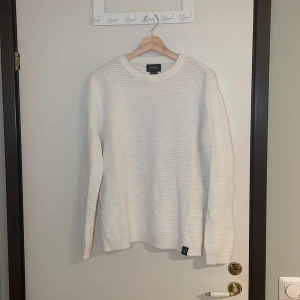 Vit stickad tröja från Pull&Bear - Säljer en stilren vit stickad tröja från Pull&Bear i mycket bra skick. Perfekt för både höst och vinter med sin mysiga och varma känsla. Tröjan har långa ärmar och en klassisk rund halsringning. Passar perfekt till både jeans och chinos för en avslappnad look. Pris går alltid att förhandlas!