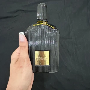 Tom Ford Black Orchid Parfym - Säljer en lyxig Tom Ford Black Orchid parfym i en elegant svart flaska med gulddetaljer. Flaskan rymmer 100 ml och har en stilren design med räfflad yta. Perfekt för den som älskar exklusiva dofter! 🌟