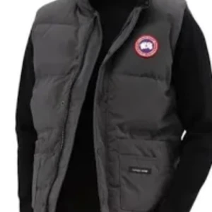 Grå dunväst från Canada Goose - Säljer en snygg och varm grå dunväst från Canada Goose. Perfekt för kyliga dagar med sin quiltade design och praktiska dragkedja. Västen har en klassisk passform och är idealisk för både höst och vinter. Den ikoniska loggan pryder bröstet. Passar perfekt över en tröja eller hoodie!
