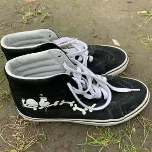 Säljer ett par coola svarta Vans sneakers med vitt tryck av peanuts och  på sidan. Skorna har vita snören och den klassiska 'Off the Wall'-loggan på hälen. Perfekta för en avslappnad stil och passar till det mesta. Använda men i bra skick!