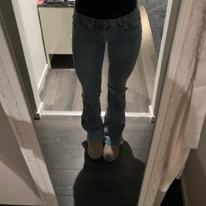 Blå bootcut jeans - Snygga blå bootcut jeans med låg midja. Perfekta för en avslappnad stil. Klassisk design med dragkedja och knappar framtill. Hålet är gjort själv
