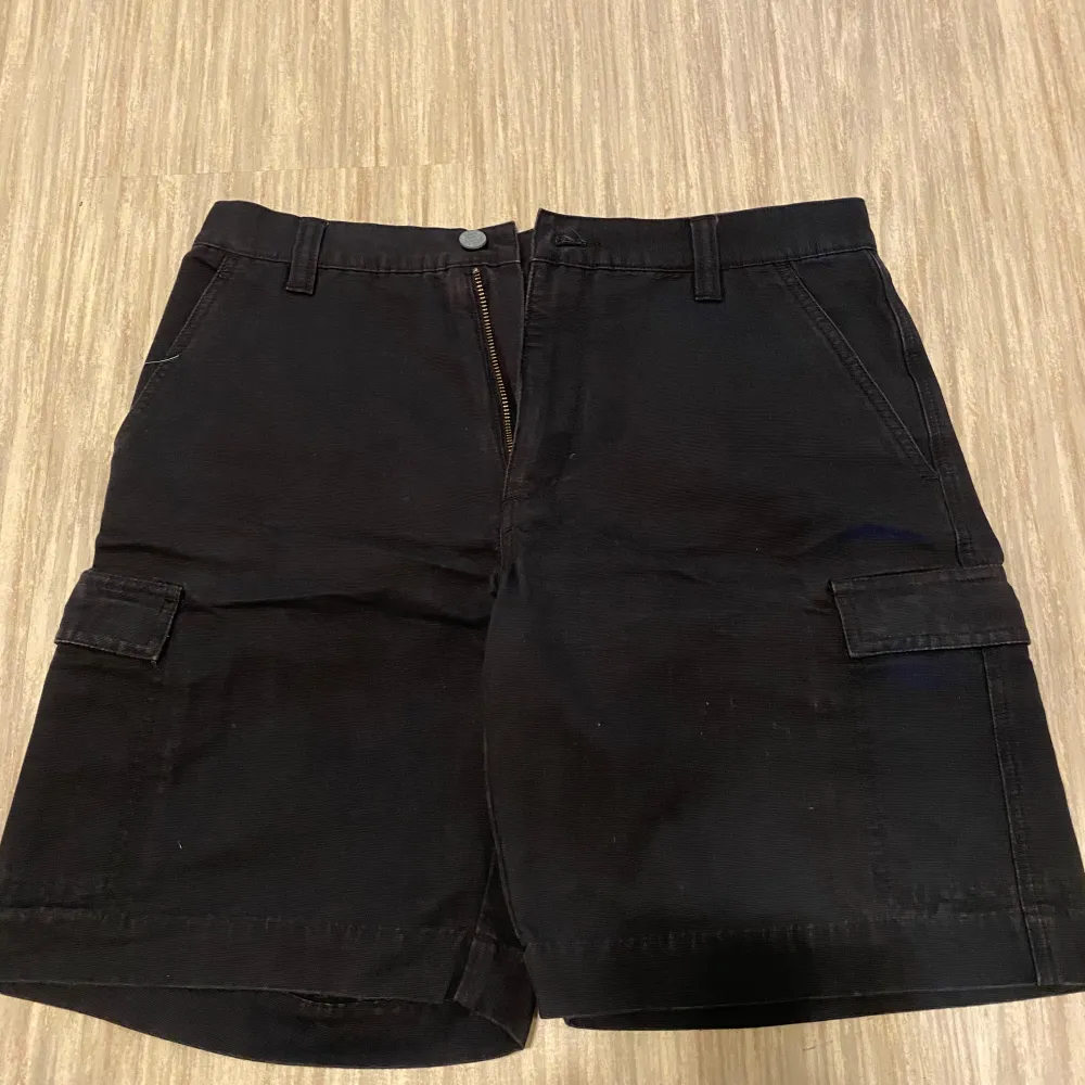 Snygga svarta cargoshorts från Eastwest med praktiska fickor på sidorna och dragkedja framtill. Perfekta för en avslappnad stil.. Shortsit.