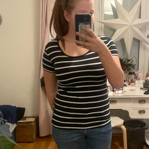 Svart och vit randig t-shirt från Basic U - Säljer en svart och vit randig t-shirt från Basic U. Den är tillverkad av ekologisk bomull och har en rund halsringning. Perfekt för en avslappnad stil. Storleken är S men passar även M