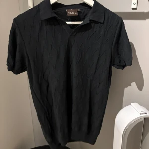 Svart pikétröja Oscar Jacosson - Oscar Jacobsson mönstrad stickad pike. Använd 1-2 gånger. Slim fit, storlek S. är 177cm och väger 66kg. 