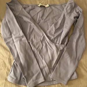 Blå/grå omlottopp - Snygg omlottopp med långärmade ärmar. Perfekt för en stilren look. Toppen har en v-ringad design och är tillverkad i ett mjukt material. Pris går o diskutera🫶🫶🫶