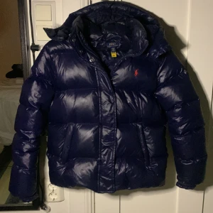 Mörkblå dunjacka från Ralph Lauren - Jag säljer denna populära Ralph Lauren dunjackan. Den är i bra skick men namnlappen på insidan av jackan har halvt lossnat (bild 5). Det är barnstorlek XL och den passar mig som är 160cm! Kom privat om ni har frågor eller för mer bilder!🥰