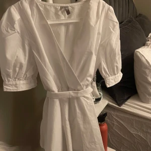 Vit blus med knytband - Säljer en stilren vit blus med korta puffärmar och knytband i midjan. Säljer då den inte kommit till användning för min del, köpt second hand med inga defekter🩷