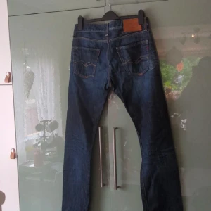Replays  - Säljer ett par klassiska mörkblå jeansbyxor med snygga sömmar och en läderdetalj vid midjan. Perfekta för en stilren look. De har en rak passform och är tillverkade i slitstarkt denim.ny skick 