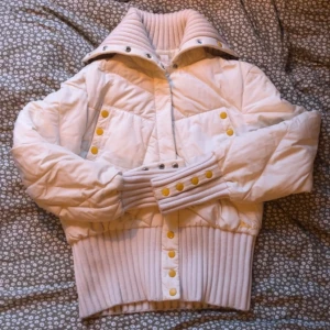 Vit quiltad jacka från Miss Sixty - SKRIV INNAN KÖP‼️Säljer en snygg vit quiltad jacka från Miss Sixty med ribbade detaljer och gulfärgade knappar. Jackan har en hög krage och långa ärmar, perfekt för kyligare dagar. Den är både stilren och bekväm. ( obs har en svart fläck på kragen men den syns inte så mycket ) skriv om ni har mer frågor, pris går att diskutera! Katt och hund finns i hemmet 😋