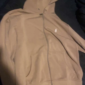 Beige huvtröja med dragkedja - Säljer en beige polo ralph lauren huvtröja med dragkedja och broderad logga på bröstet. Tröjan har långa ärmar och en praktisk huva med dragsko. Perfekt för en avslappnad och fräsch stil. Nytt pris bara koftan på Zalando storlek s som själva huvtröjan är kostar 2259 ni får även med byxor 1700 vid snabb och smidig affär kan jag går ner lite 
