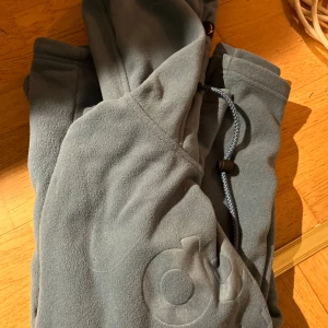 Grå fleece hoodie från Dope ( Pris kan diskuteras) - Säljer en grå fleece hoodie från Dope med tryck. Hoodien har en justerbar huva och en stor ficka framtill. Perfekt för kyliga dagar eller när man åker skidor!
