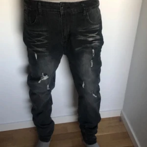 Svart jeans  - Snygga svarta jeans med coola slitningar och en modern look. De har en klassisk femficksdesign och en bekväm passform. Perfekta för en avslappnad stil.