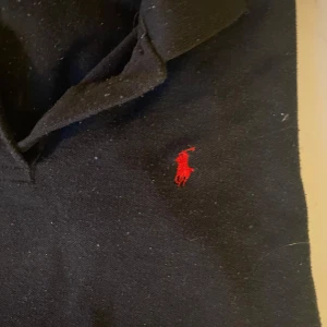 Svart pikétröja från Ralph Lauren - Snygg svart pikétröja från Ralph Lauren med klassisk krage och röd broderad logotyp på bröstet. Perfekt för en stilren look. Nypris 1700, mitt pris 449. Pris går och diskutera 