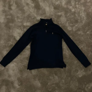 Mörkblå tröja från Ralph Lauren - Säljer en stilren mörkblå tröja från Ralph Lauren den är en Halfzip och har den klassisk logga på bröstet. Perfekt för en avslappnad men snygg look.