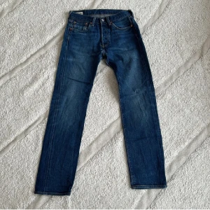 Levis 501 - Klassiska Levis 501 jeans i en snygg blå färg. De har en straight passform och är tillverkade i slitstarkt denim. Perfekta för en avslappnad stil.