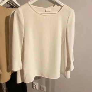 Vit blus från Vila - Elegant vit blus från Vila med trekvartsärm och rund halsringning. Perfekt för en stilren look.