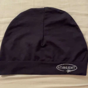 Svart mössa från Starlight - Snygg svart mössa från Starlight med en enkel design. Perfekt för att hålla värmen under kyliga dagar. Den har en diskret logga framtill.