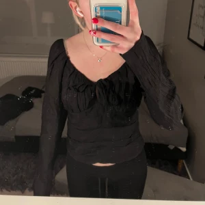 Svart topp med rosett - snygg svart topp med långärmade ärmar och en söt rosett framtill, skriv om ni har frågor!