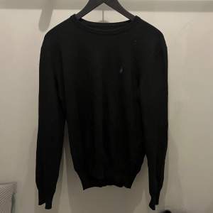Snygg svart tröja från Ralph Lauren med diskret logga på bröstet. Tröjan har en klassisk design med rund hals och långa ärmar. Perfekt för en stilren look. Framgår ingen storlek på tröjan men jag skulle säga M