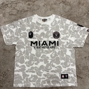 Vit och grå camo t-shirt från A Bathing Ape - Snygg vit och grå camo t-shirt från A Bathing Ape med Miami-tryck. Pris kan diskuteras.