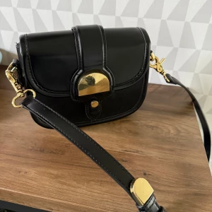 Väska - Svart väska ifrån zara med gulddetaljer🤍 i bra skick! Ganska liten men rymmer mycket