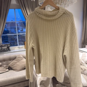 Beige ribbad polotröja - Säljer en mysig beige ribbad polotröja med långa ärmar. Perfekt för kyliga dagar och ger en stilren look. Tröjan har en avslappnad passform och är gjord i ett mjukt material.
