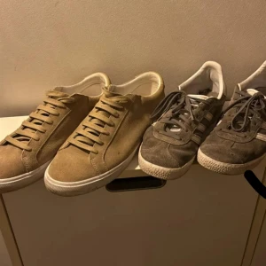 Beige och grå sneakers - Två par sneakers, ett i beige mocka med snörning och ett i grå mocka med vita detaljer. Perfekta för en avslappnad stil.