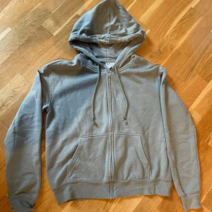 Ljus grön hoodie från H&M Divided - Säljer en ljus grön hoodie från H&M Divided. Den har en dragkedja framtill och en mysig huva med dragsko. Perfekt för en avslappnad stil. 