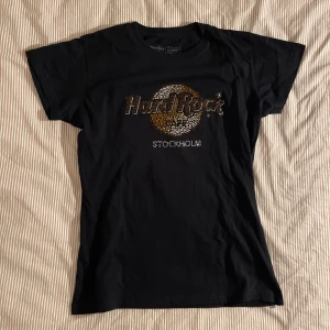 Svart t-shirt från Hard Rock Café - Snygg svart t-shirt från Hard Rock Café med glittrig logga och texten 'Stockholm' på framsidan. Storlek S
