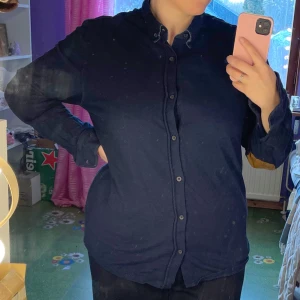 Mörkblå skjorta från Hampton Republic - Säljer en stilren mörkblå skjorta från Hampton Republic. Skjortan har långa ärmar och knappar framtill. Den har snygga bruna armbågslappar som ger en extra touch. Perfekt för en avslappnad men ändå uppklädd look. storlek XL. Lite tjockare material, passar till det mesta!