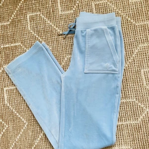 Juicy Couture Del Ray baby blue stl S - Snygga ljusblå byxor från Juicy Couture i en mjuk och bekväm velour. Perfekta för en avslappnad stil. Något smutsiga längst ner på benen och framsida ben. Går ev att få bort med fläckrengöring. Men helhetsintrycket är bra. 