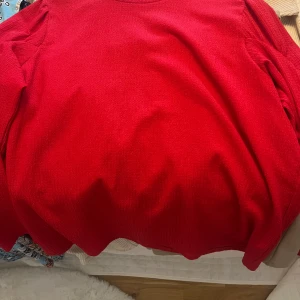 Röd stickad tröja - Säljer en härligt röd stickad tröja med långa ärmar. Perfekt för kyligare dagar och ger en färgklick till din garderob. Tröjan har en enkel och stilren design som passar till många olika outfits.