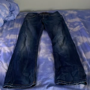 Mörkblå jeans från Nudie Jeans - Snygga mörkblå jeans från Nudie Jeans med klassisk design. De har en rak passform och är tillverkade i slitstarkt denim. Perfekta för en avslappnad stil.