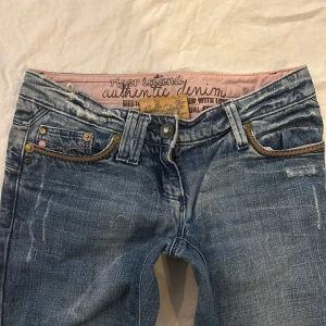 Vintage jeans från River Island med låg midja och flared ben - Vintage jeans från river island i storlek XS. De har en låg midja och en flared passform. Jag kan tyvärr inte visa hur dessa sitter på då de inte passar mig. Midja: 35,5, grenmått: 16,5, innerbenslängd: 82cm, benöppning: 22,5cm notera att knappen har rostat och att det är en slitning högst upp vid midjan på baksidan av jeansen 