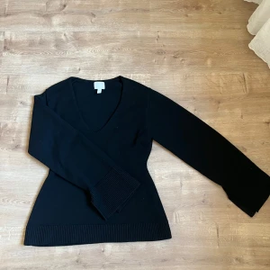 Svart v-ringad tröja - Snygg svart tröja med v-ringning och långa ärmar. Perfekt för en stilren look. Ribbstickade muddar vid ärmslut och nederkant ger en fin detalj. Även åtsittande i midjan. 