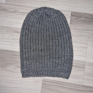 Grå ribbad mössa - Snygg grå ribbad mössa. Den är stickad och har en enkel design som gör den lätt att matcha med olika outfits. Mössan är hemmastickade.
