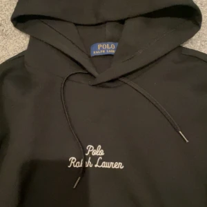 Svart hoodie från Ralph Lauren - Snygg svart hoodie från Ralph Lauren med broderad logga på bröstet och ikonisk hästlogga på ärmen. Hoodien är 100% äkta och köpt från zalando för 2200kr. Nästan aldrig använda så den är perfekt ny skick. Rekommenderas för dig som är 170-180 om du är smal till och med längre.