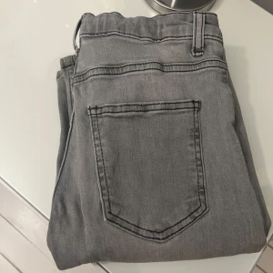 Grå jeansbyxor - Snygga grå jeansbyxor med klassisk femficksdesign och knappgylf. Perfekta för en avslappnad stil. Storlek 164.