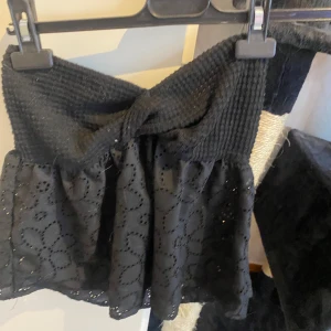 Svart topp från Shein - Säljer en svart topp från Shein med en ribbad överdel och broderade detaljer på nederdelen. Toppen har en knytning framtill och är ärmlös. Perfekt för en stilren look.