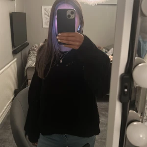 Svart stickad tröja - Säljer en svart stickad tröja med ett fint hålmönster. Tröjan har långa ärmar och en avslappnad passform, perfekt för kyligare dagar. Lite nopprig men priset är satt med tanske på det