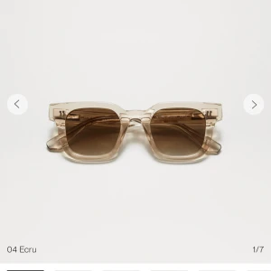 Beige solglasögon från Chimi - Snygga solglasögon från Chimi, 04 Ecru. De har en fyrkantig form med transparenta bågar och mörka linser. Perfekta för en solig dag och kommer i ett elegant fodral.