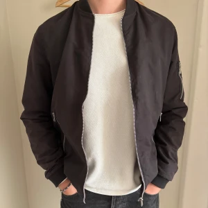 Svart bomberjacka från Jack & Jones - Säljer min svarta bomberjacka från Jack&Jones med dragkedja framtill och fickor med dragkedja. Bra jacka inför våren. Storlek S, men fungerar bra för mig som är 183. 