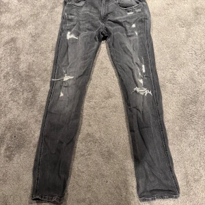 Grå jeans från Replay - Snygga grå jeans från Replay i modellen Anbass. De har en cool slitningseffekt och en klassisk femficksdesign. Perfekta för en avslappnad stil med en touch av edge.