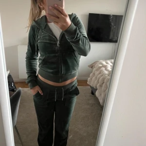 Juicy couture set - Säljer detta snygga mörk gröna juciy couture set med dragkedja framtill. Tröjan har långa ärmar och en bekväm passform, perfekt för en avslappnad stil. Den är mjuk och skön att ha på sig. Settet är i bra skick, använt endast några gånger. Nypris runt 2000