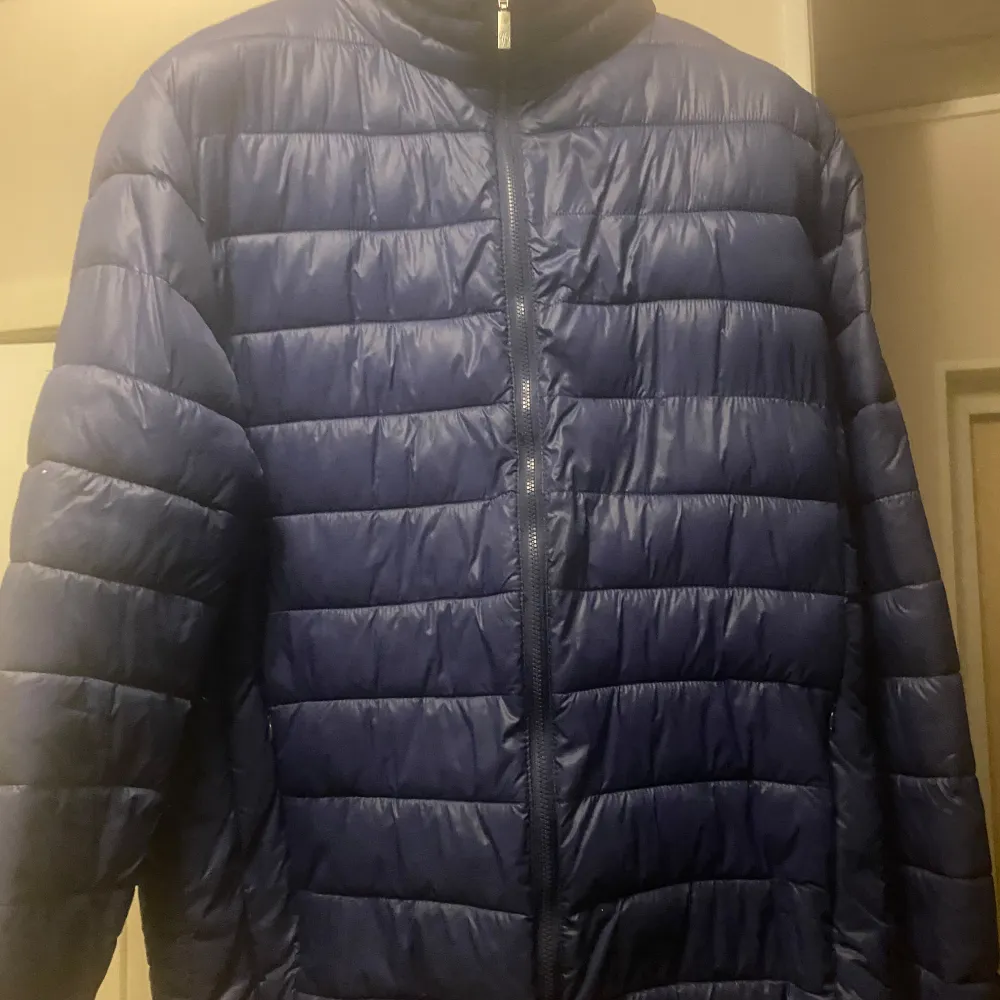 Säljer en snygg blå quiltad jacka från Moncler. Den är perfekt för kyligare dagar med sin pufferstil och långa ärmar. Jackan har en dragkedja framtill och är i nyskick. Den har också en cool detalj med ett märke på ärmen. Perfekt för både höst och vinter!. Jackor.