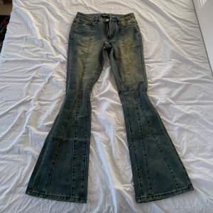 Säljer ett par snygga bootcut jeans i en klassisk blå färg. De har en skön passform och är perfekta för både vardag och fest. Jeansen har en dragkedja och knappar framtill samt fickor både fram och bak.