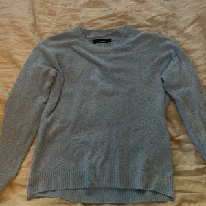 Ljusblå stickad tröja - Säljer en supermysig ljusblå stickad tröja. Den har en enkel design med långa ärmar och ribbade kanter vid ärmslut och nederkant. Perfekt för kyliga dagar när du vill vara både varm och stilren. Passar till både jeans och kjol! Den har en liten fläck