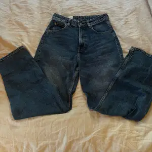 Säljer ett par klassiska blå jeans i en loose passform. De har en hög midja och raka ben, vilket ger en avslappnad och bekväm stil. Perfekta för vardagsbruk! De är 90’s Baggy jeans.