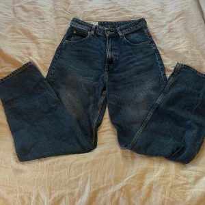 Blå jeans - Säljer ett par klassiska blå jeans i en loose passform. De har en hög midja och raka ben, vilket ger en avslappnad och bekväm stil. Perfekta för vardagsbruk! De är 90’s Baggy jeans.