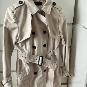 Beige trenchcoat  - En fin beige trenchcoat från Zara. Den är i väldigt bra sick samt inte använd så många gånger. Den har inga skavanker överhuvudtaget!